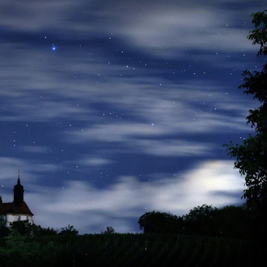 ARCHIV - 13.08.2023, Bayern, Volkach: Eine Sternschnuppe verglüht am Himmel über der Wallfahrtskirche Maria im Weingarten.