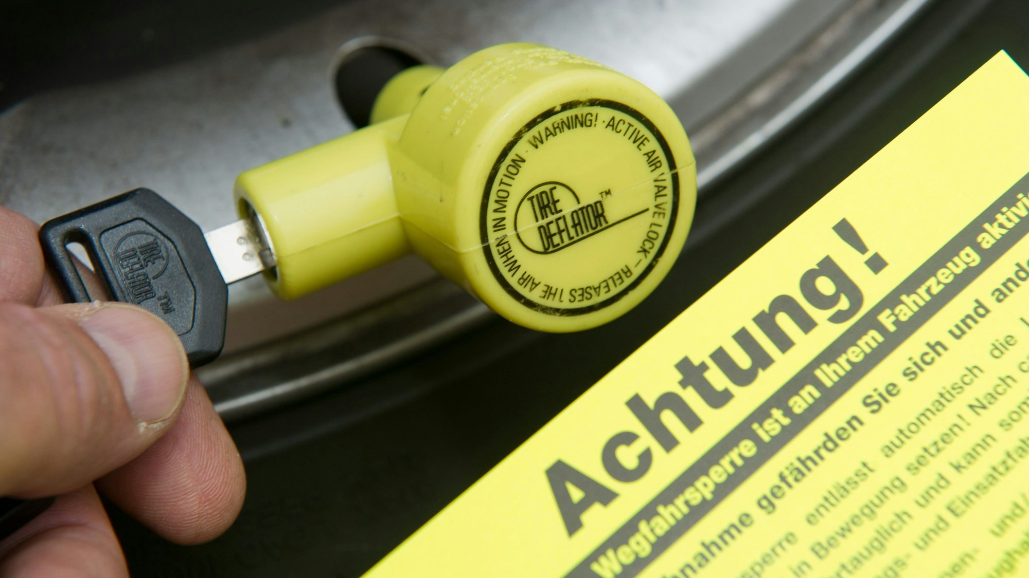 Am Ventil eines Pkw-Reifens schließt ein Mann einen so genannten «Ventilwächter» an.