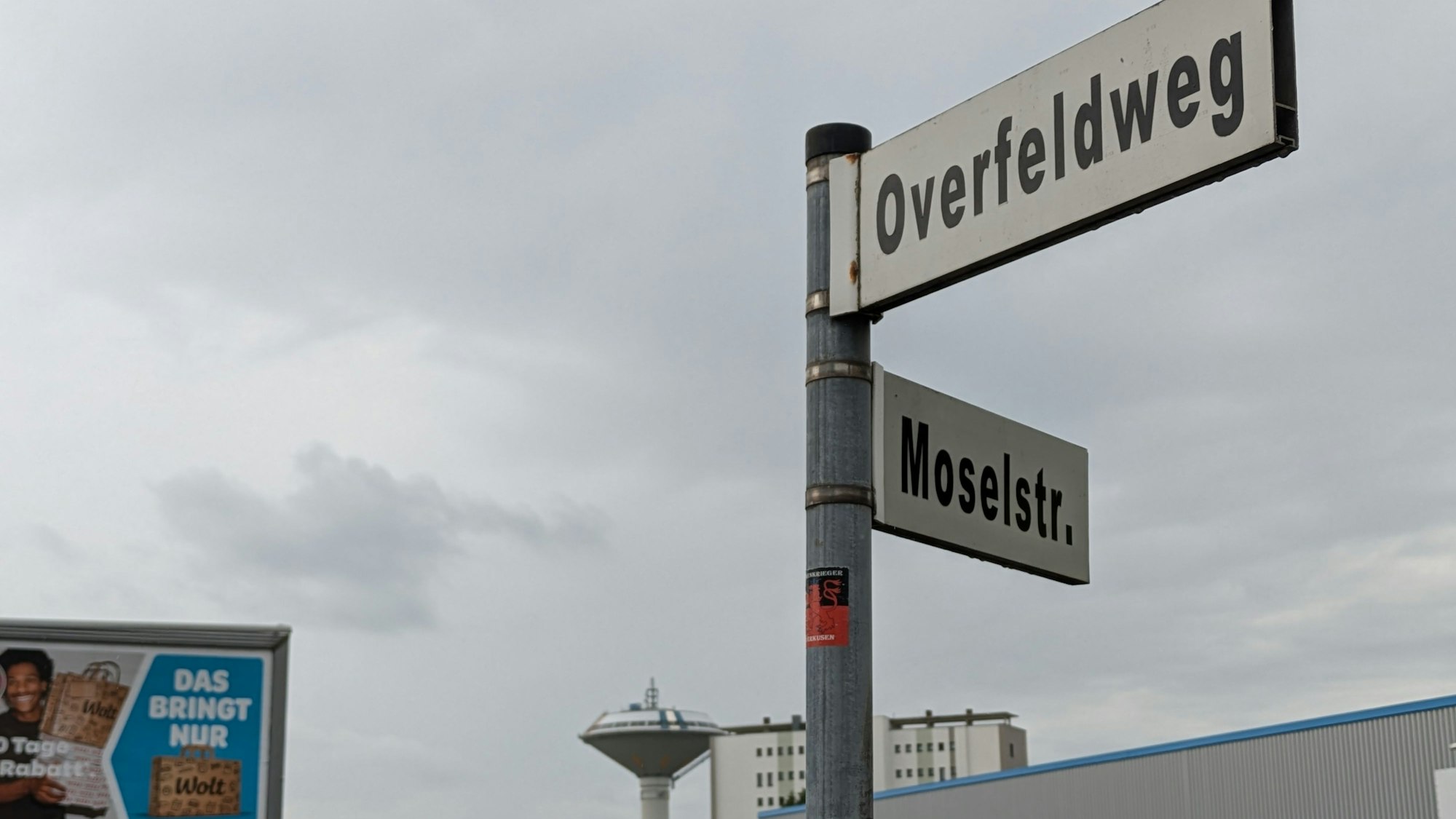 Straßenschild Overfeldweg in Bürrig mit Wasserturm im Hintergrund