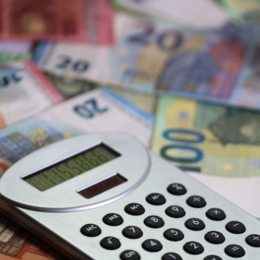 Ein Taschenrechner liegt auf verschiedenen Euro-Banknoten.