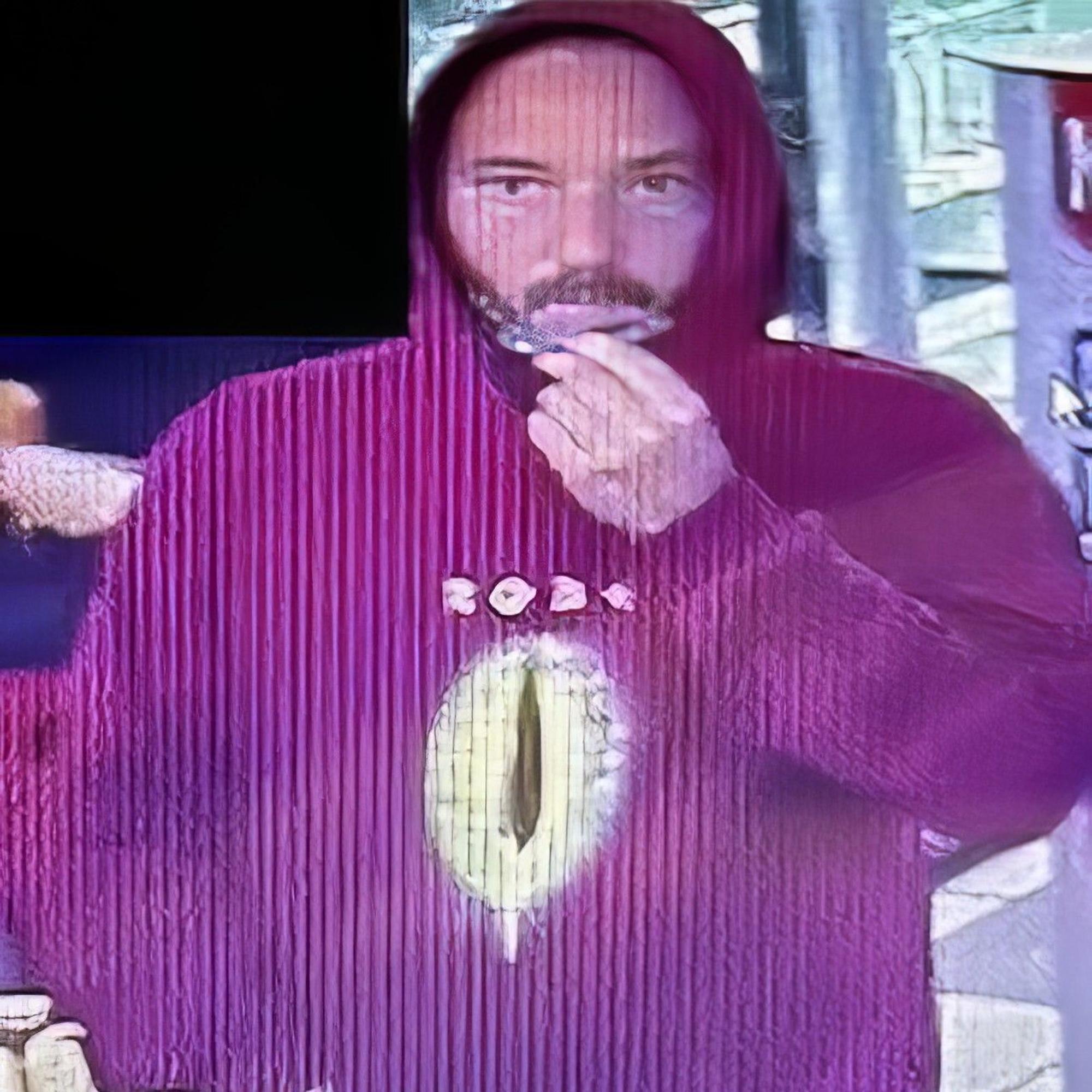 Der Mann trägt einen roten Kapuzenpulli mit einem Emblem auf der Brust.