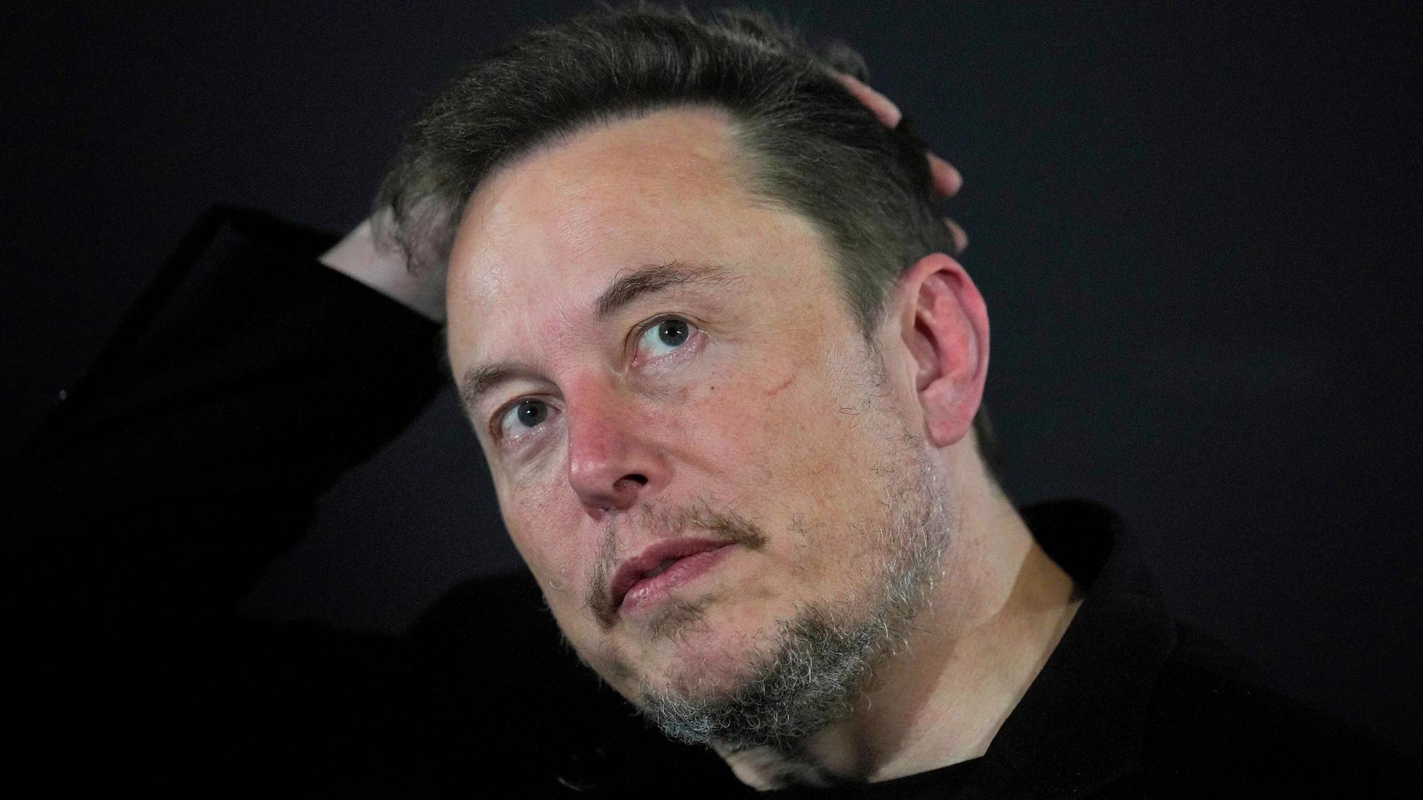 Bild von Elon Musk, der sich mit einer Hand über den Kopf fährt.