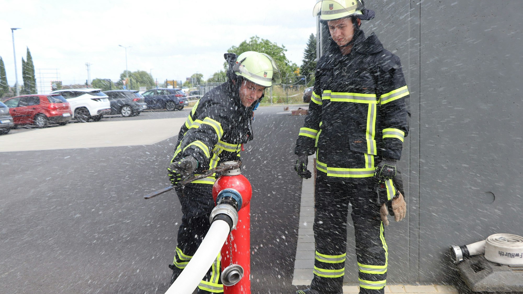 Zwei Feuerwehrmänner arbeiten an einem Hydranten.