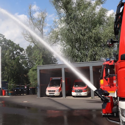 Zu sehen ist Löschwasser, das im hohen Bogen aus einem Schlauch kommt.