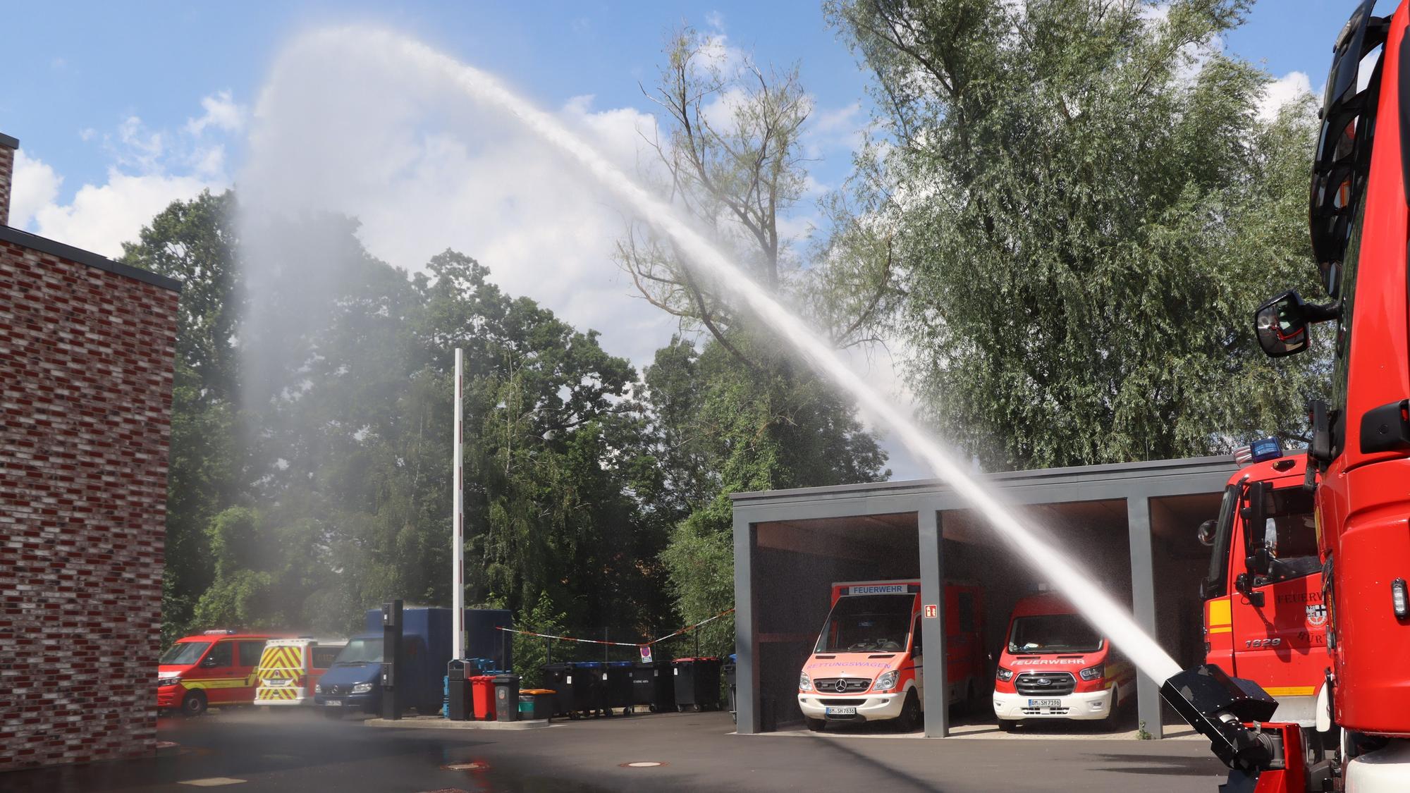 Zu sehen ist Löschwasser, das im hohen Bogen aus einem Schlauch kommt.