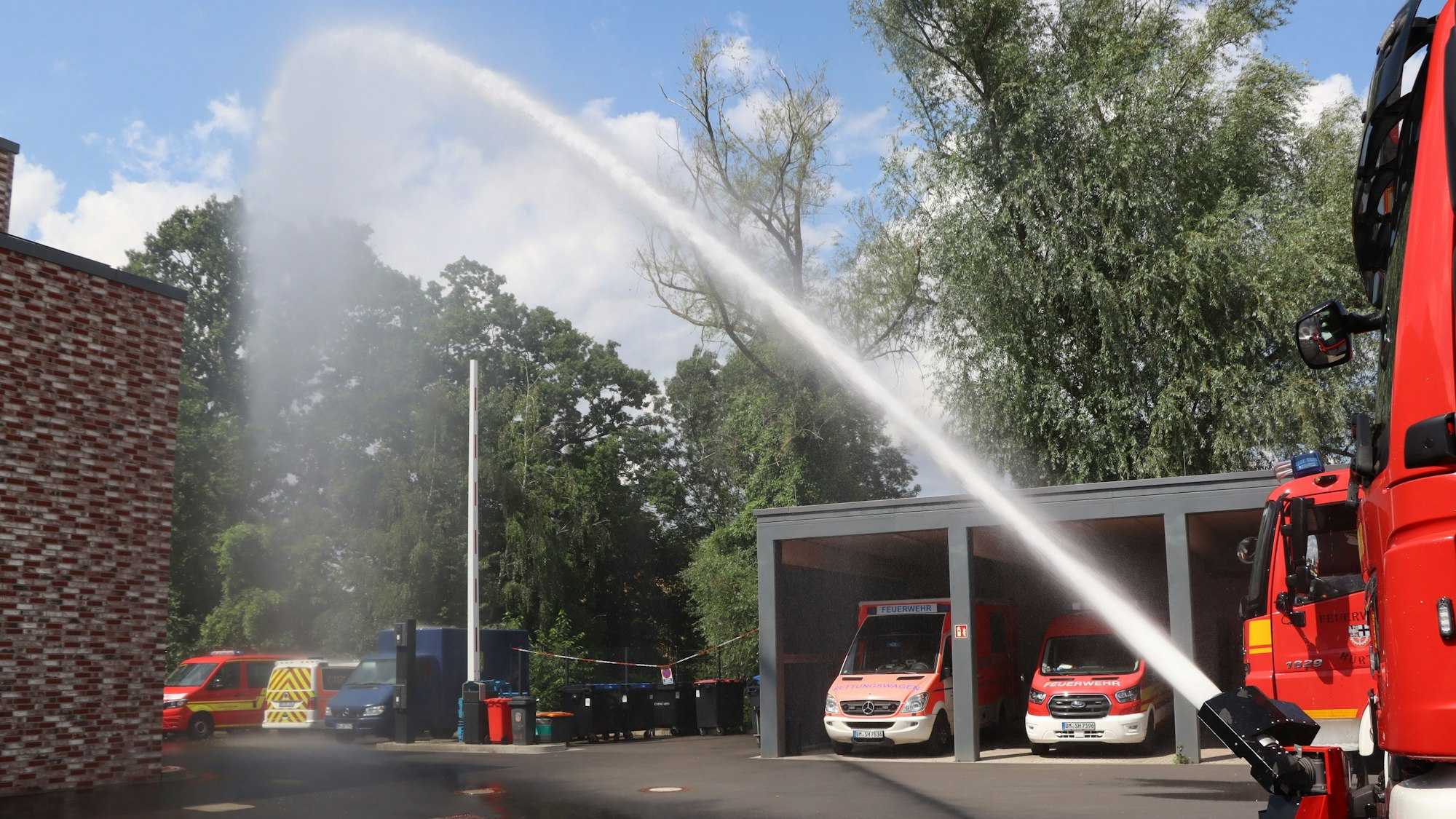Zu sehen ist Löschwasser, das im hohen Bogen aus einem Schlauch kommt.