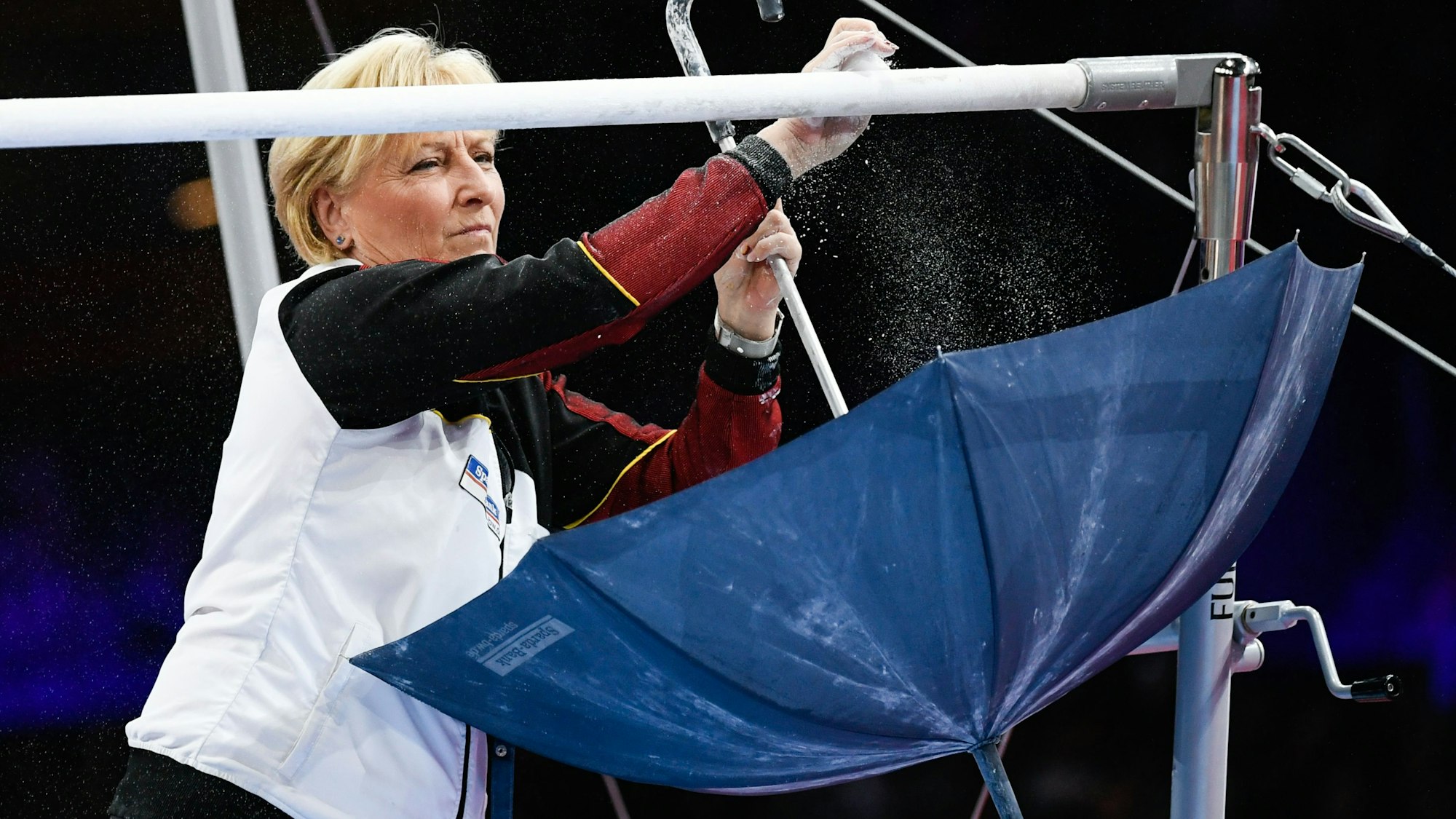 Das Foto zeigt Ulla Koch, wie sie den Stufenbarren für die nächste Turnerin vorbereitet.