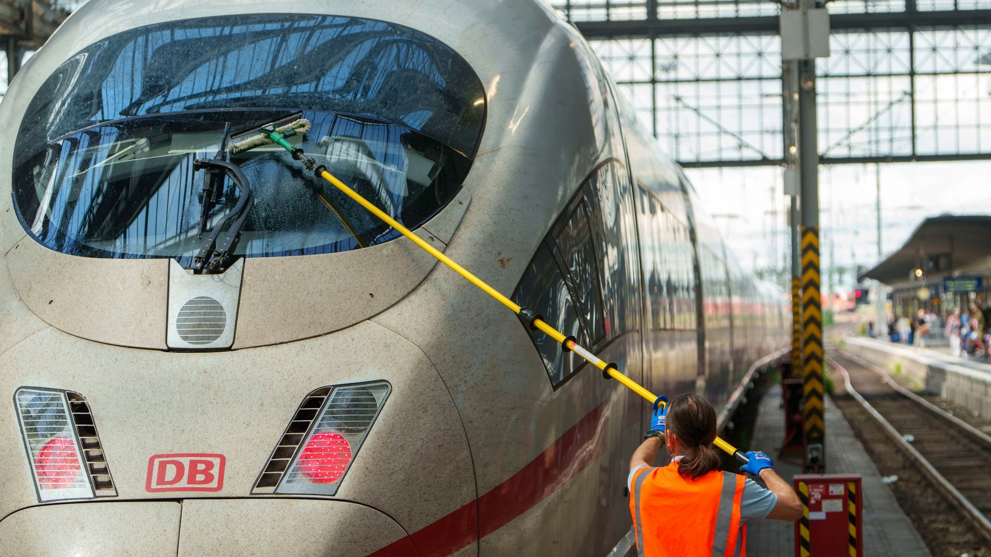 Ein Servicemitarbeiter reinigt im Hauptbahnhof die Frontscheibe eines ICE.