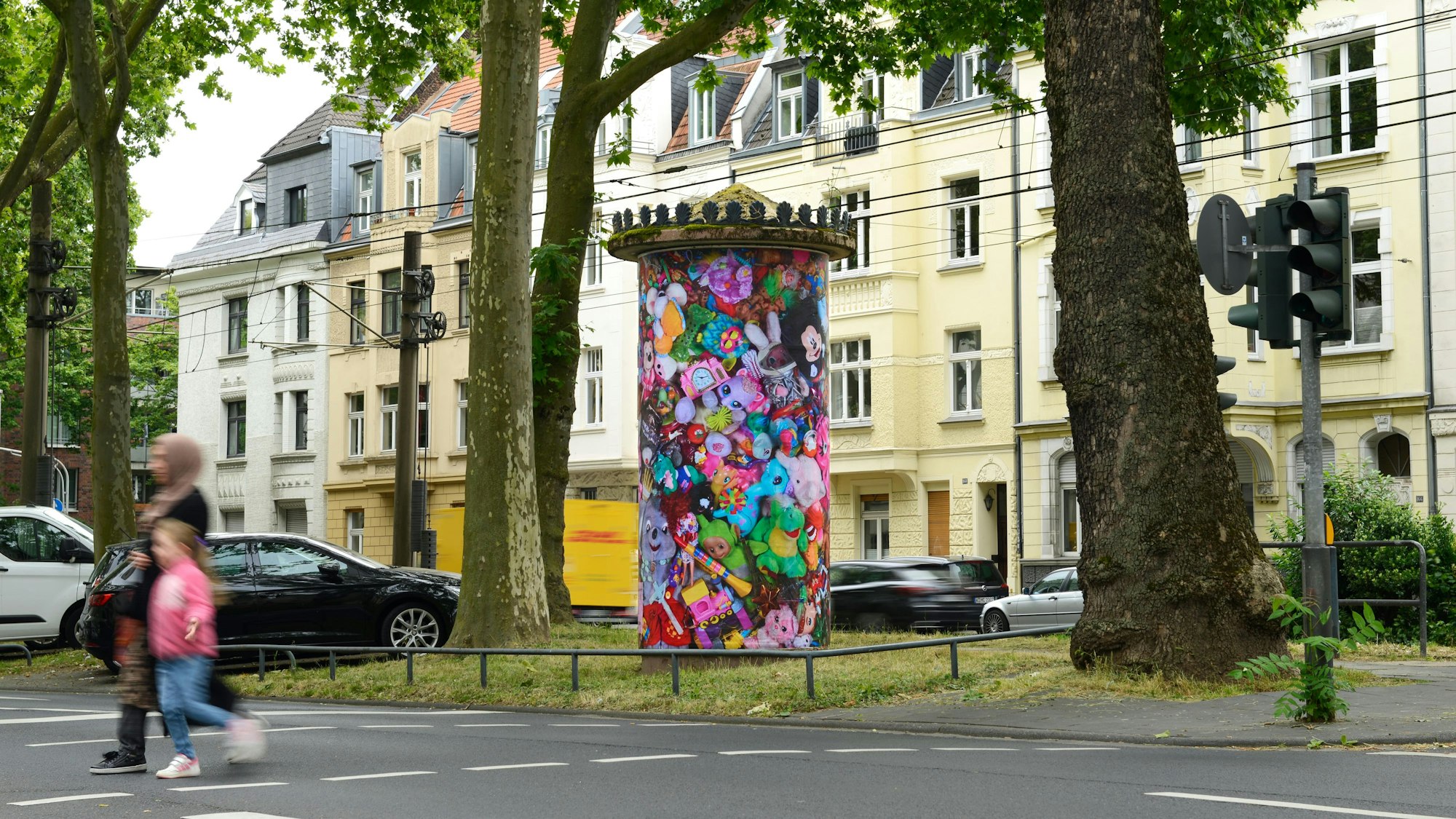 Eine Litfaßsäule mit einem Kunstwerk in Köln.