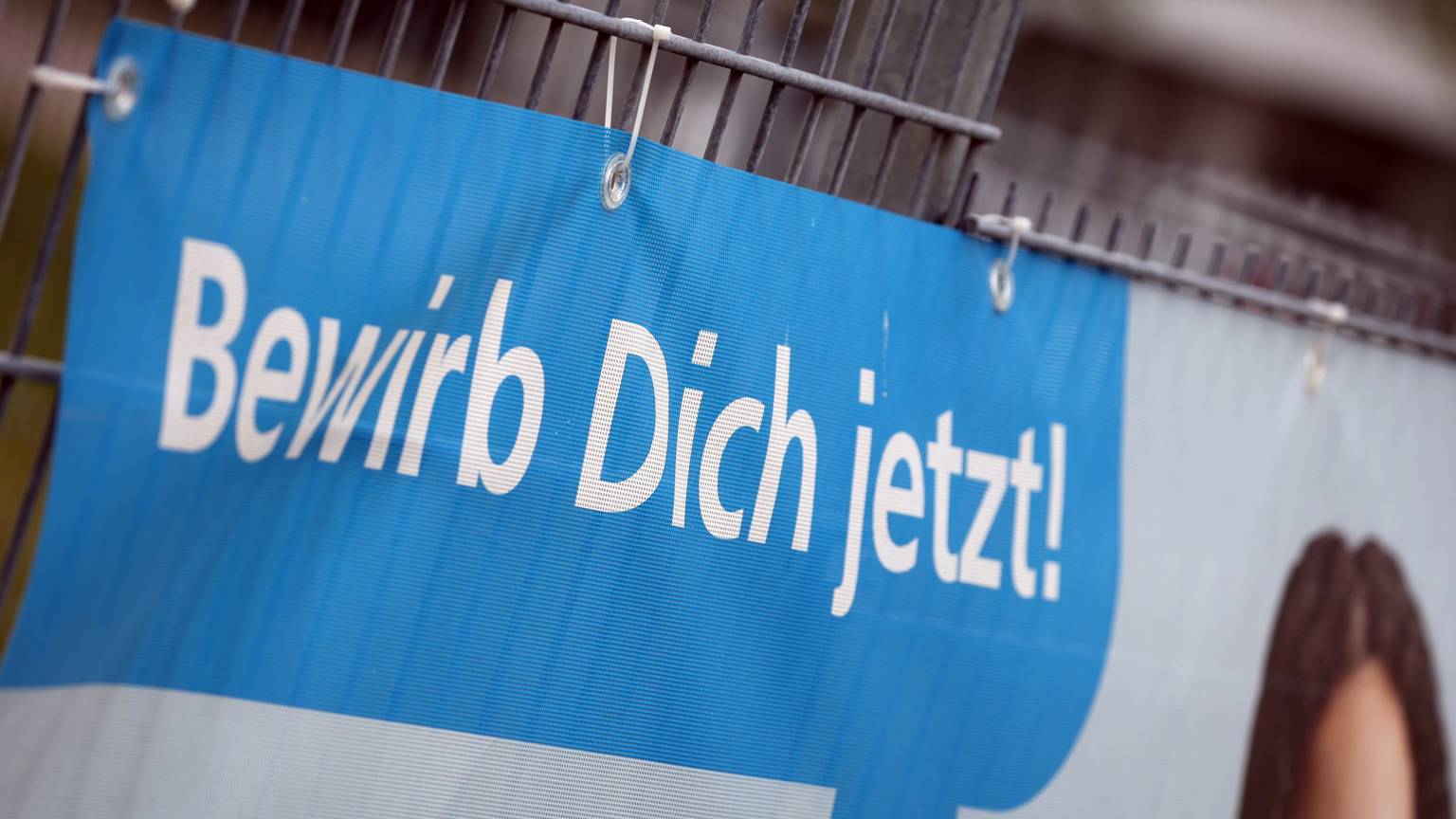 «Bewirb dich jetzt» ist auf einem Transparent am Zaun einer Firma zu lesen, die für Auszubildende im Handwerk wirbt.