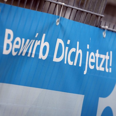 «Bewirb dich jetzt» ist auf einem Transparent am Zaun einer Firma zu lesen, die für Auszubildende im Handwerk wirbt.
