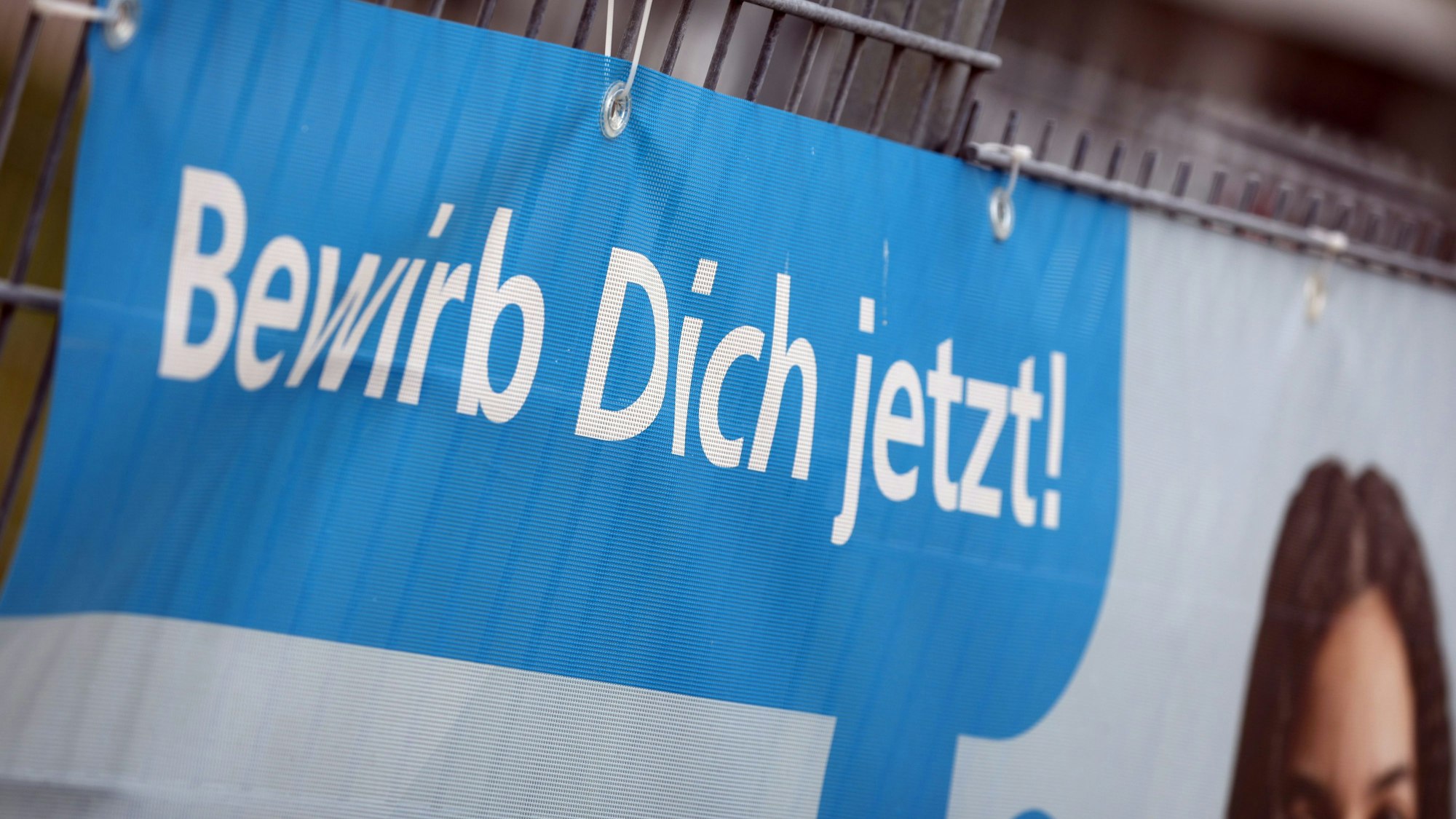 «Bewirb dich jetzt» ist auf einem Transparent am Zaun einer Firma zu lesen, die für Auszubildende im Handwerk wirbt.