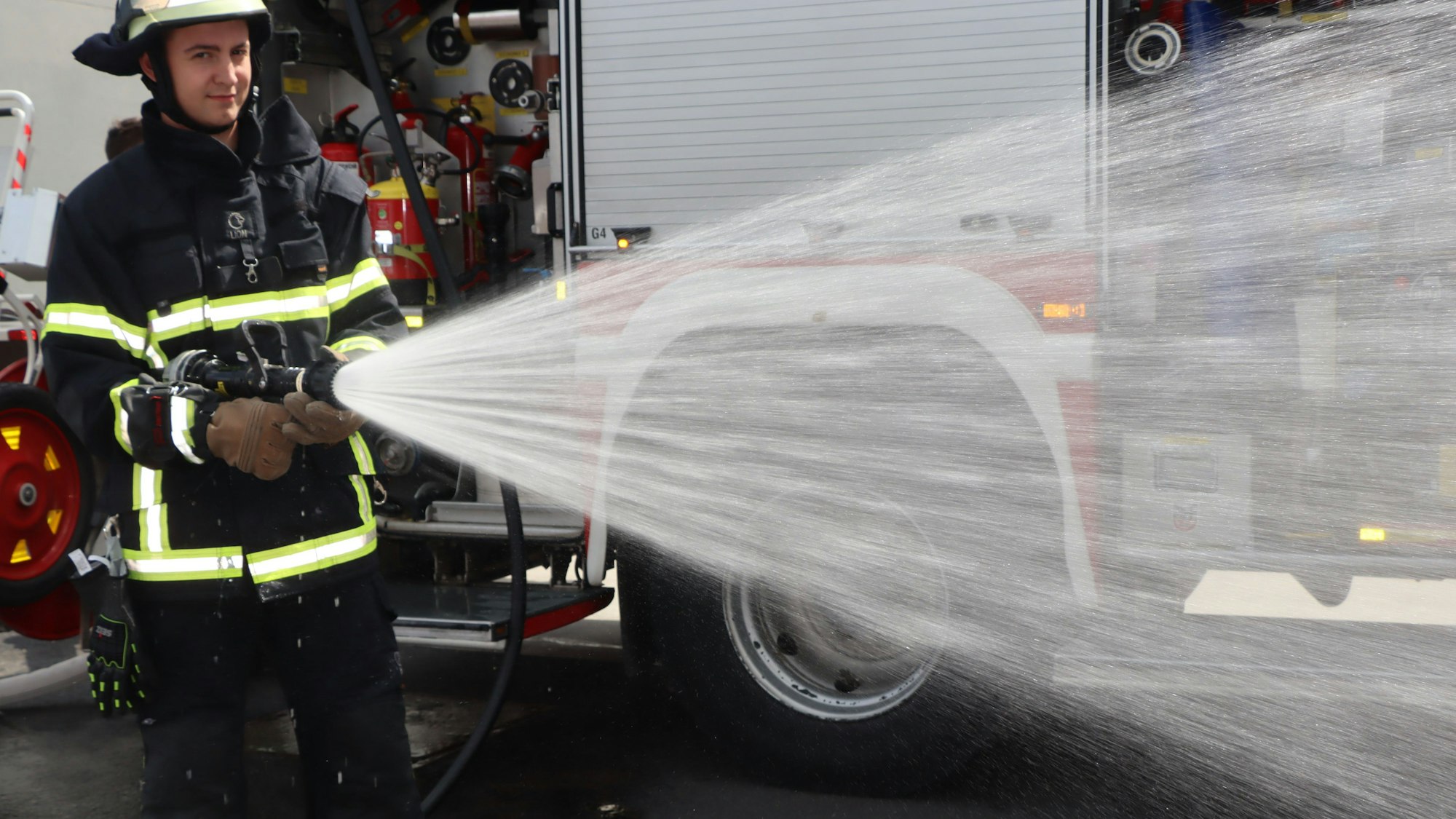 Ein Feuerwehrmann hält einen Schlauch, aus dem Wasser kommt.