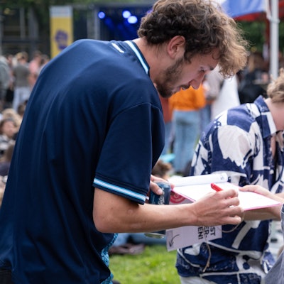 Ein Mann hält einer jungen Frau ein Klemmbrett zum Unterschreiben entgegen.