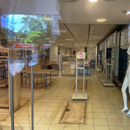 Ein Blick durch die großen Fenster im ehemaligen Kaufhof zeigt leere Regale und nackte Schaufensterpuppen.