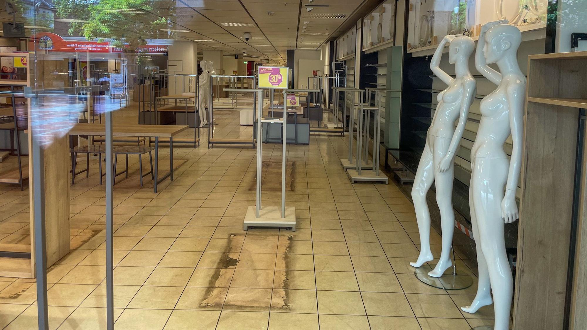 Ein Blick durch die großen Fenster im ehemaligen Kaufhof zeigt leere Regale und nackte Schaufensterpuppen.