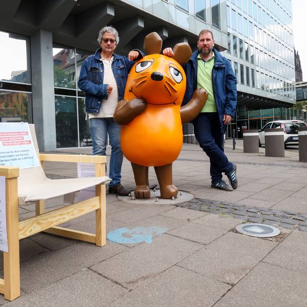 Zu sehen sind zwei Männer, die vor dem WDR-Filmhaus in Köln stehen.