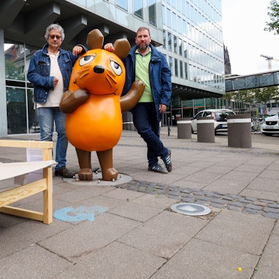 Zu sehen sind zwei Männer, die vor dem WDR-Filmhaus in Köln stehen.