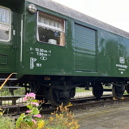 Ein grüner Eisenbahnwaggon steht auf einem eigens dafür angelegten Gleisbett.
