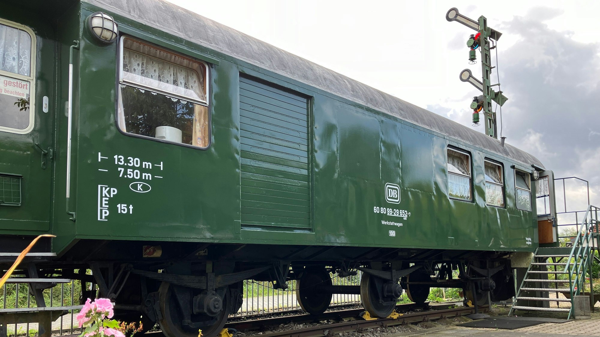 Ein grüner Eisenbahnwaggon steht auf einem eigens dafür angelegten Gleisbett.