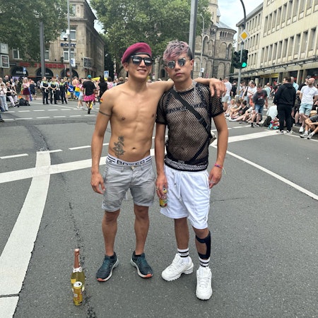 Zwei Personen stehen nebeneinander. Im Hintergrund viele Menschen.