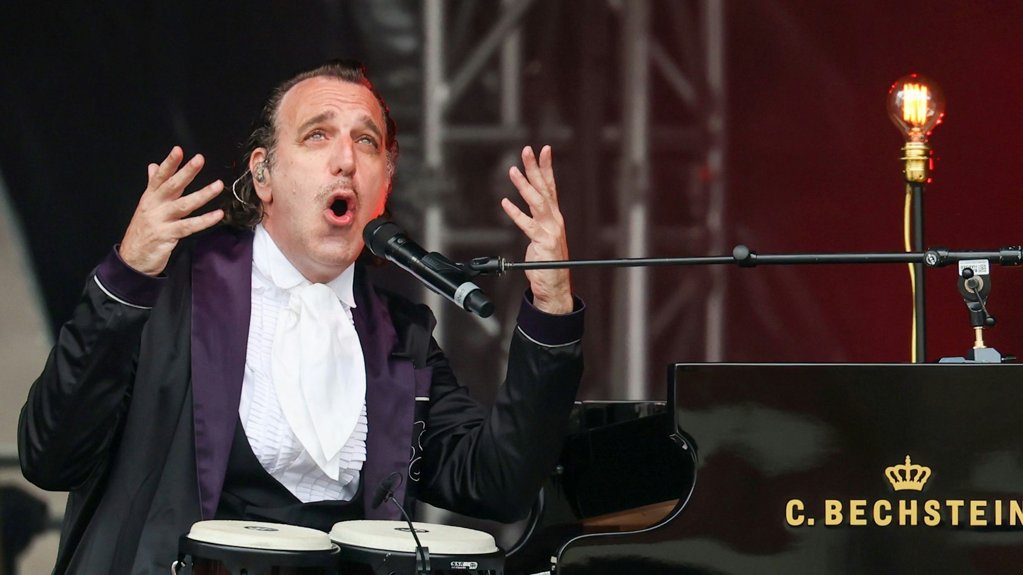 Chilly Gonzales bei seinem Konzert vor dem Kölner Dom auf dem Roncalliplatz im Juli 2024 – zwischen Bongo-Trommeln und Bechstein-Flügel.