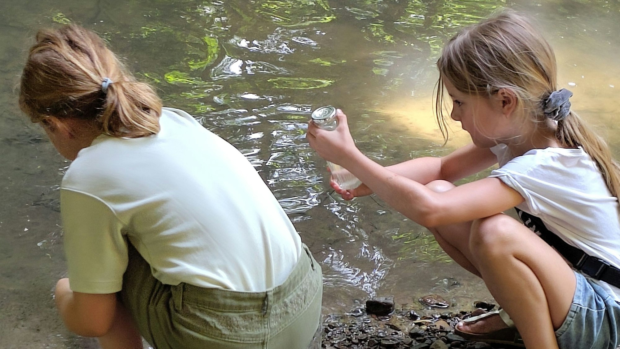 Zwei Mädchen schöpfen Wasser aus der Dhünn.