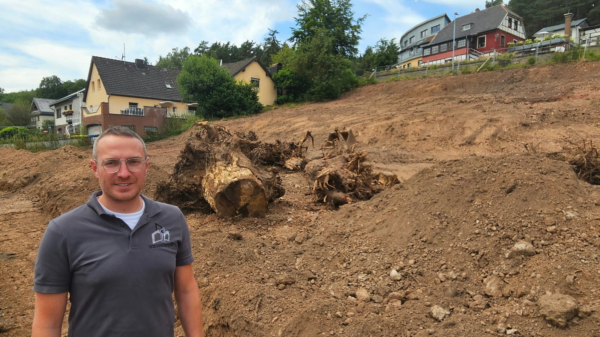 Thomas Mahlberg steht vor einigen Baumwurzeln, die auf dem Grundstück liegen.