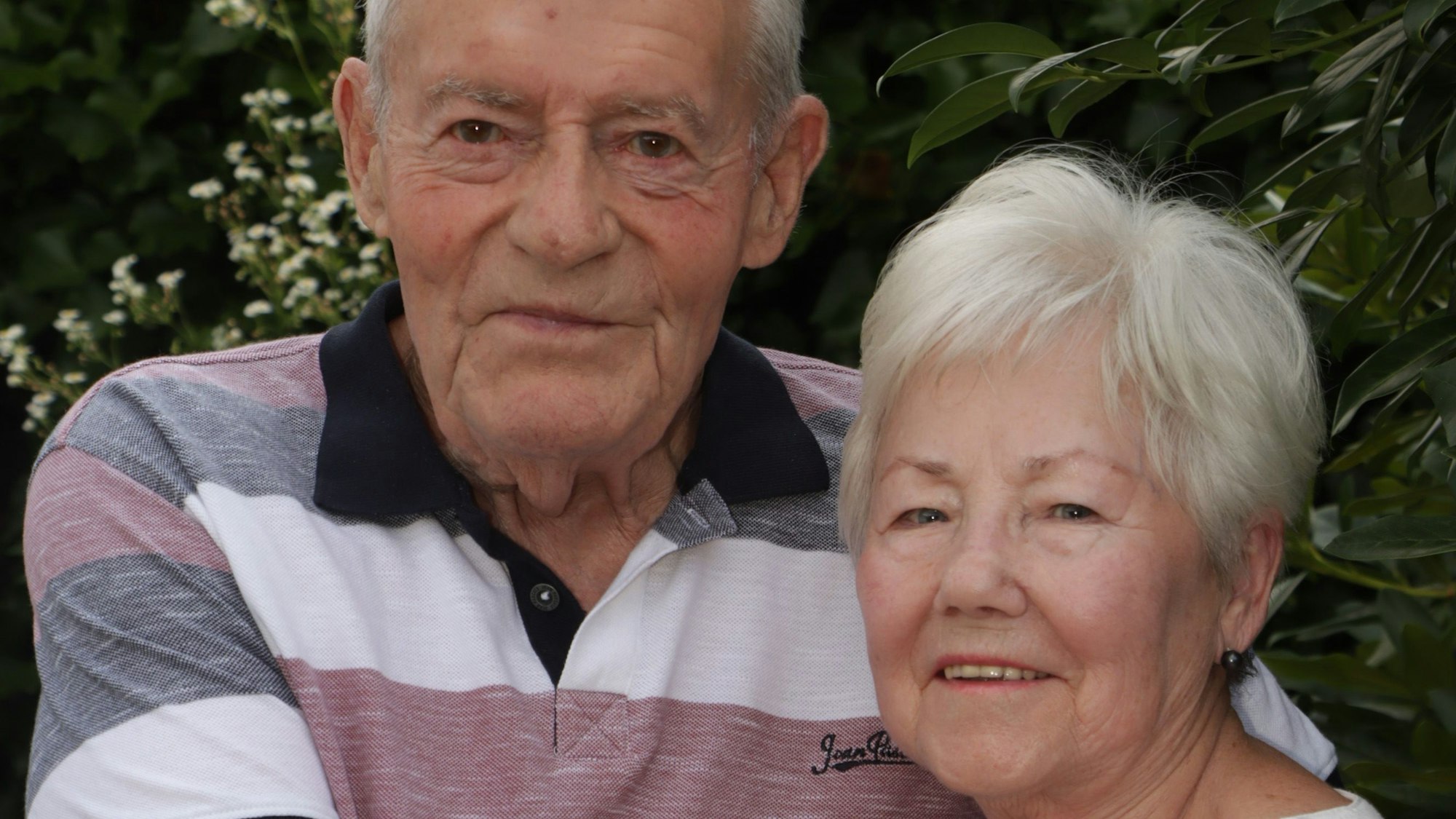 Ein älterer Mann und ältere Frau lächeln.