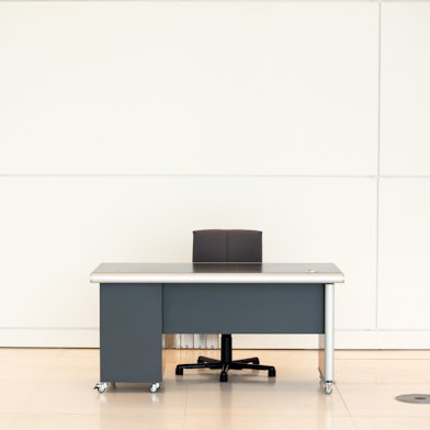 Ein leerer Schreibtisch und ein Bürostuhl stehen vor einer Wand.