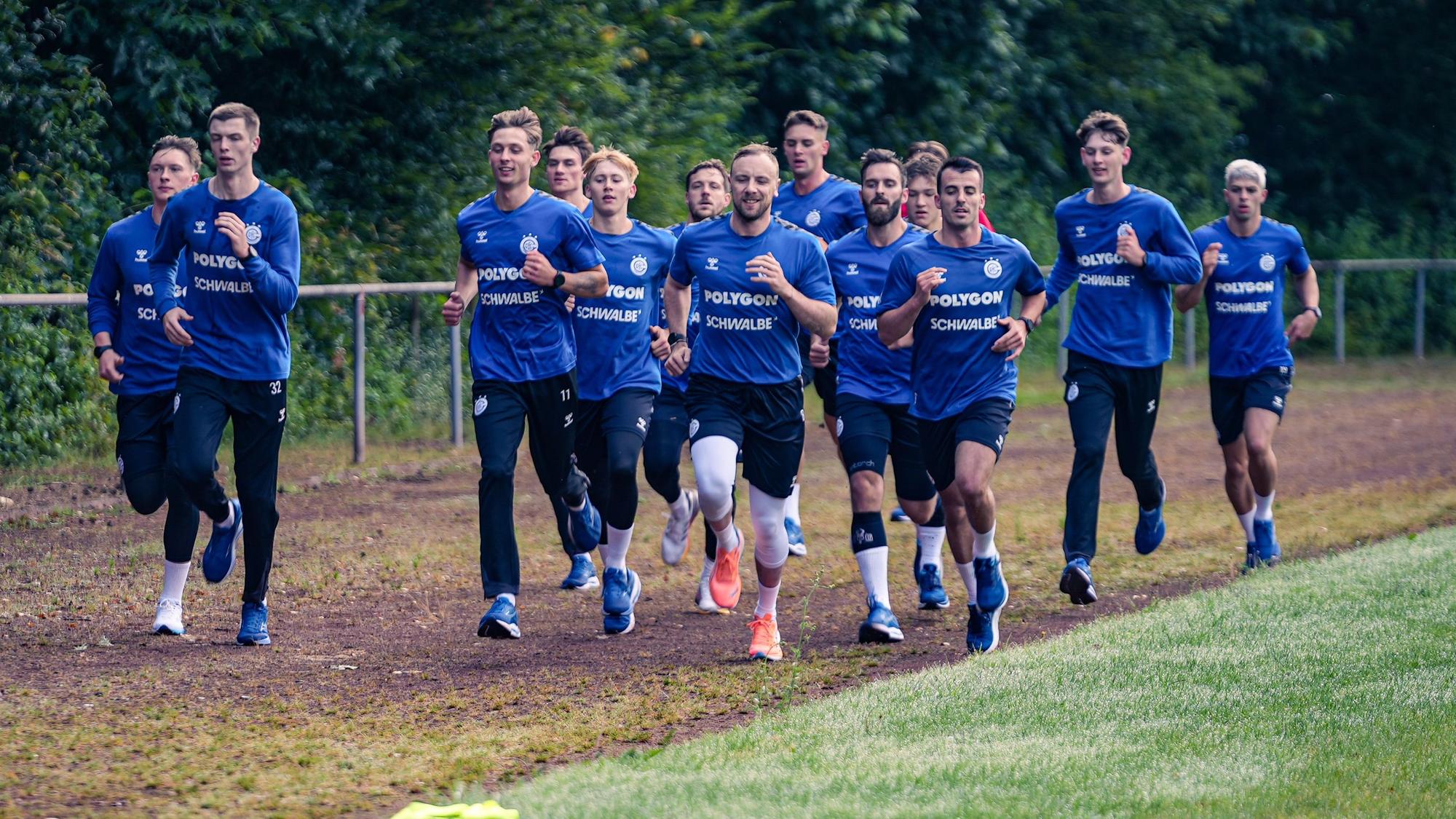 Zu sehen ist eine Handballmannschaft beim Laufen über das Trainingsgelände.