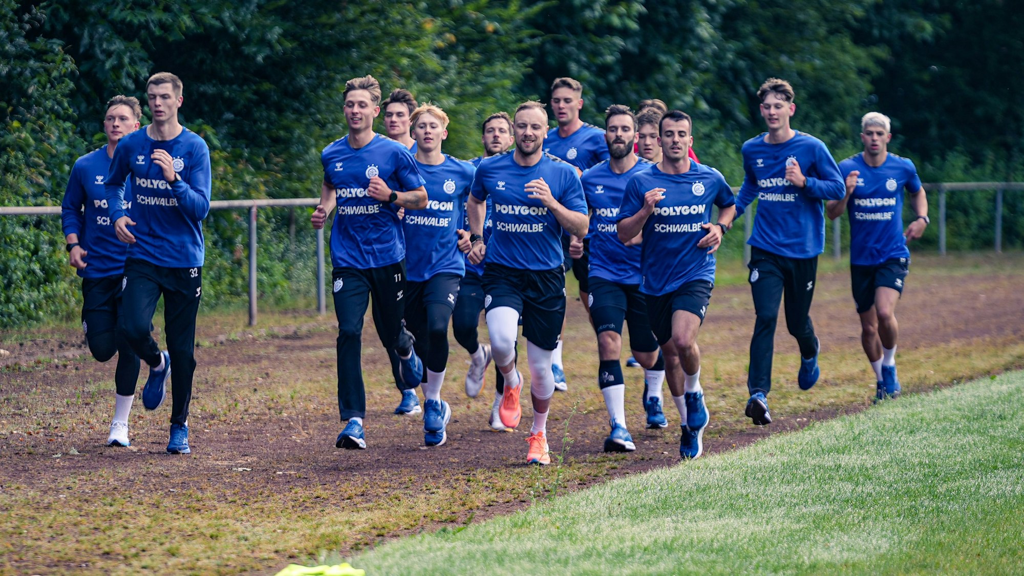 Zu sehen ist eine Handballmannschaft beim Laufen über das Trainingsgelände.