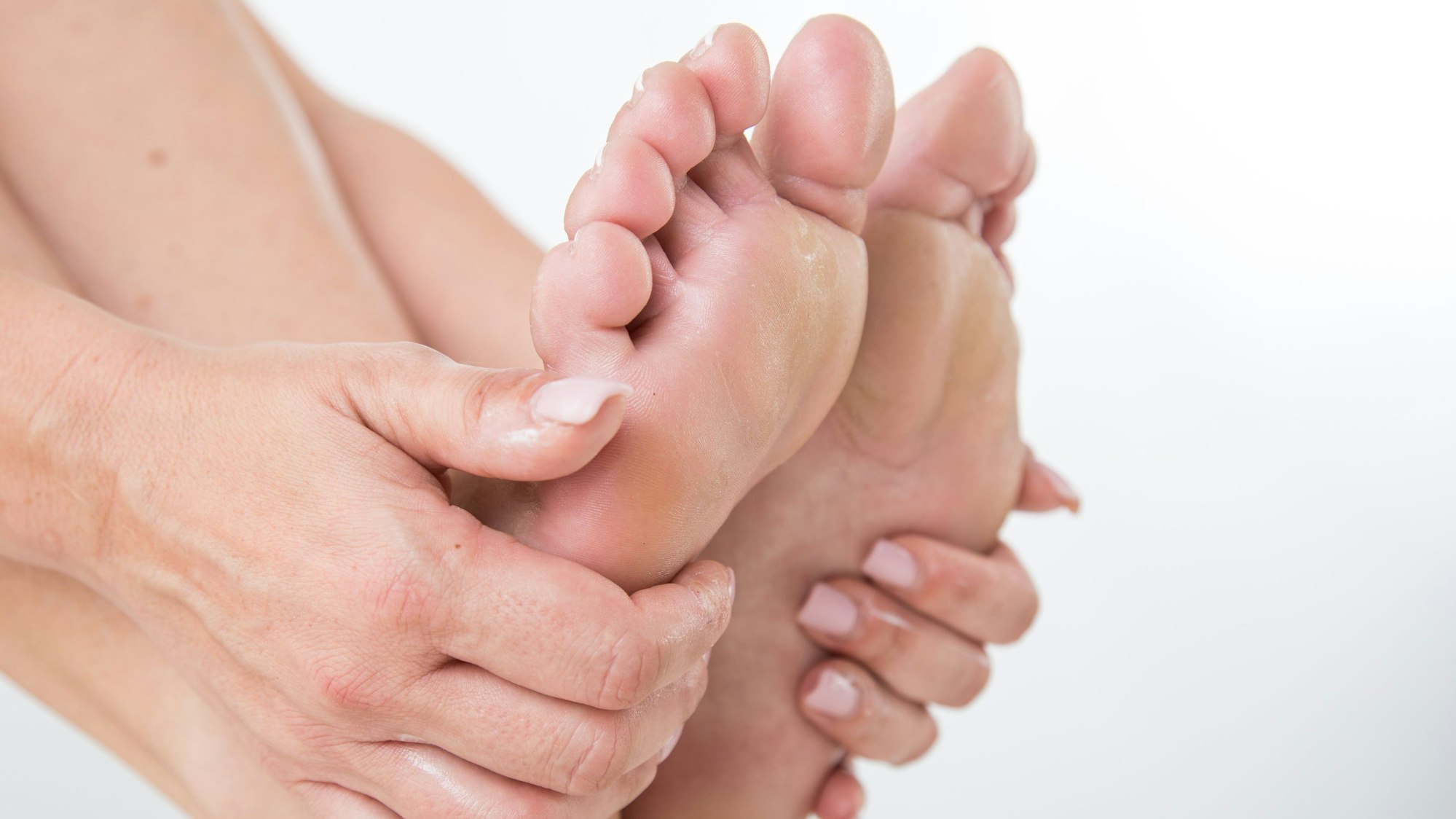 Zu sehen sind Füße, die von Händen umfasst werden.