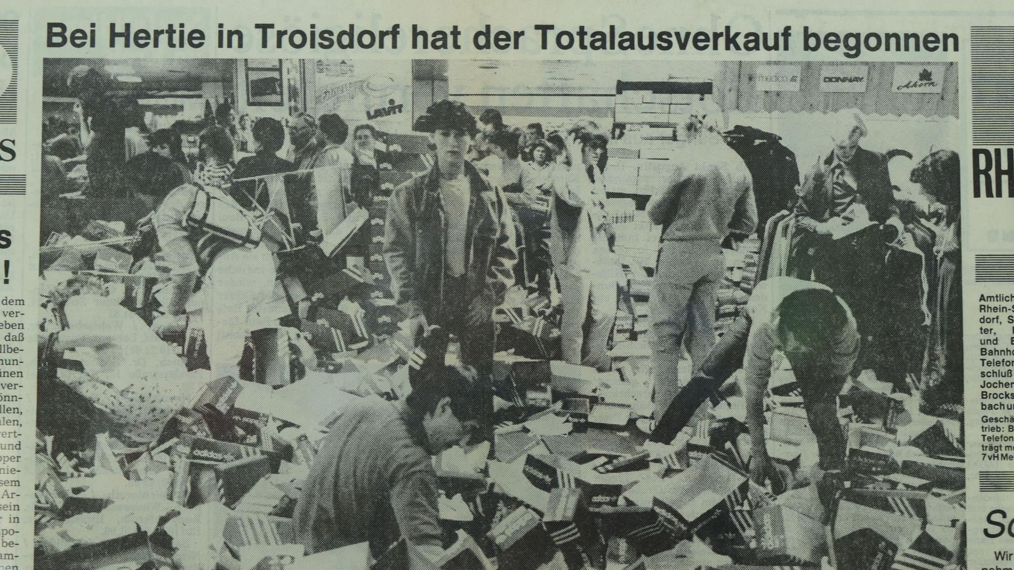 Ein altes Zeitungsfoto zeigt Menschen, die auf einem Berg von Schuhkartons stehen und wühlen.