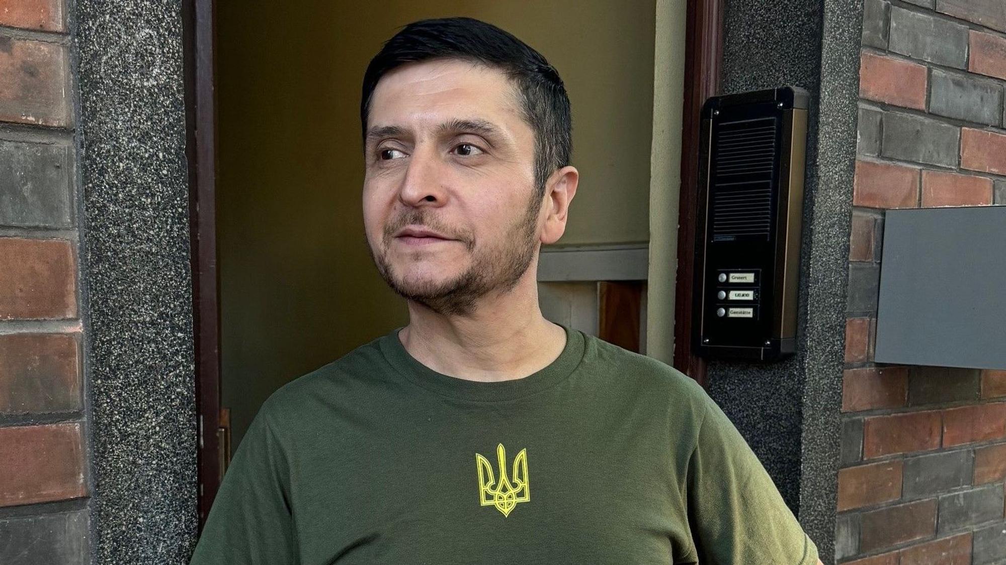 Das Selenskyj-Double Umid Isabaev aus Usbekistan steht an einer Haustüre vor einer Stadt im Ruhrgebiet. Ihm droht die Abschiebung.
