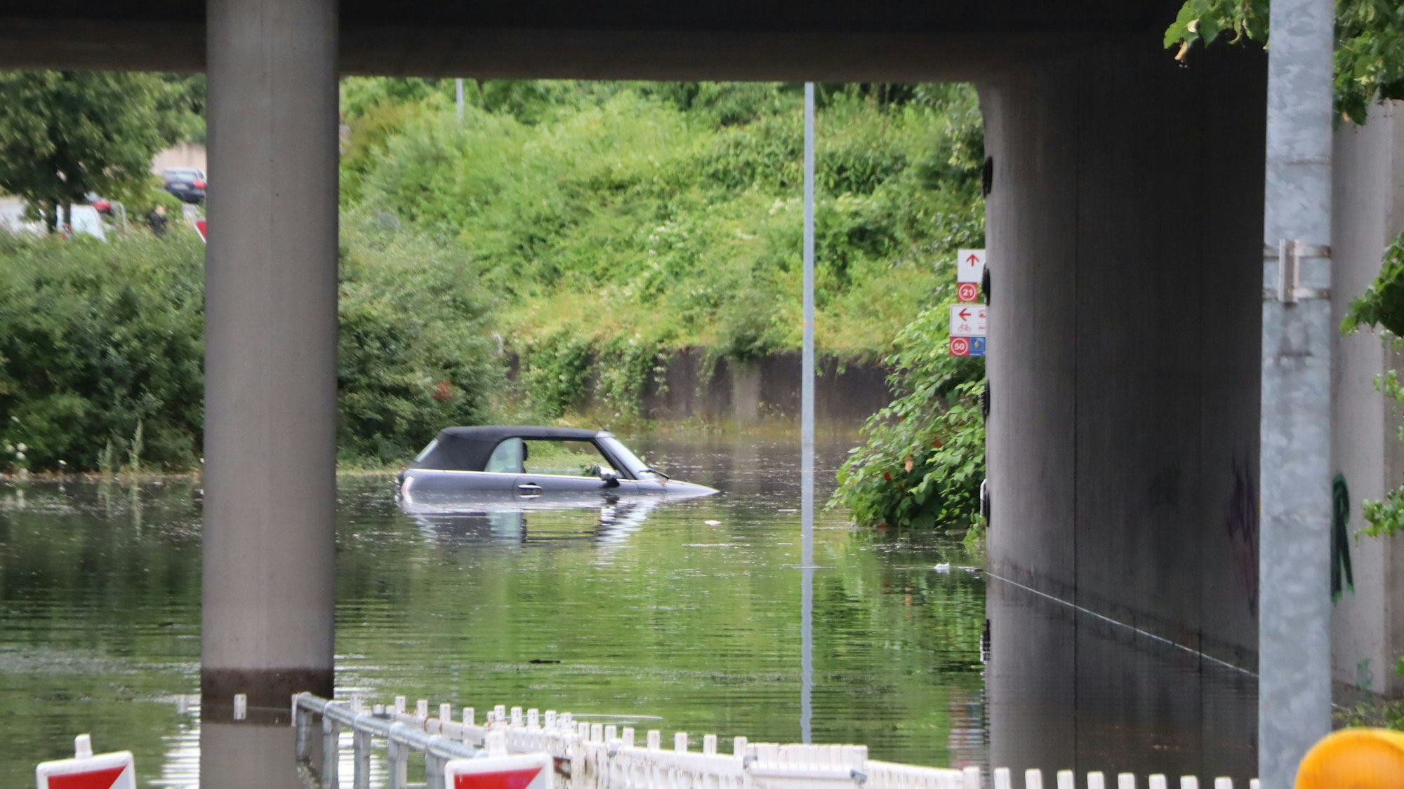 Ein Auto steht in einer mit Wasser vollgelaufenen Unterführung.