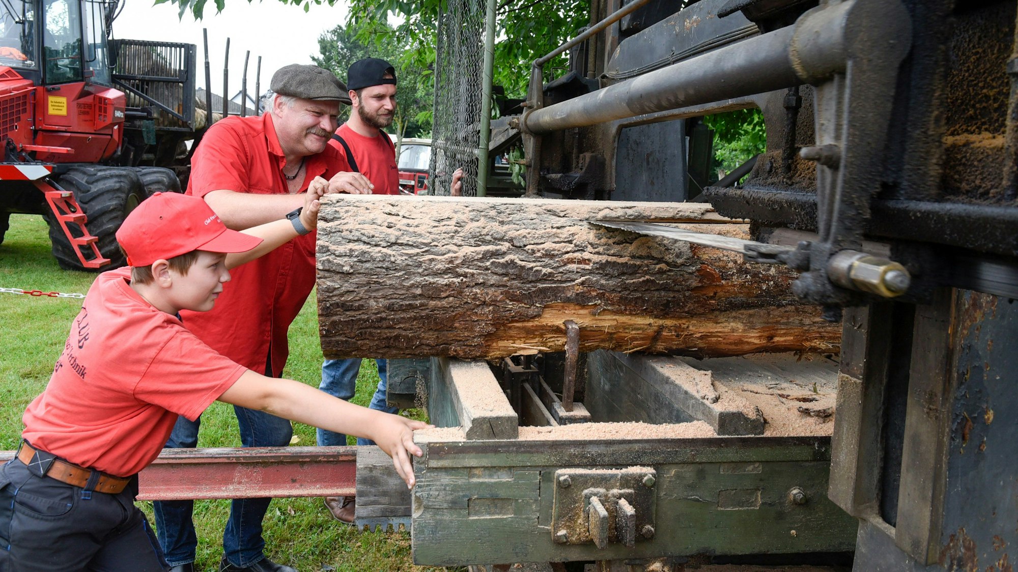 Zwei Männer und ein Junge an einer speziellen Holzsäge.