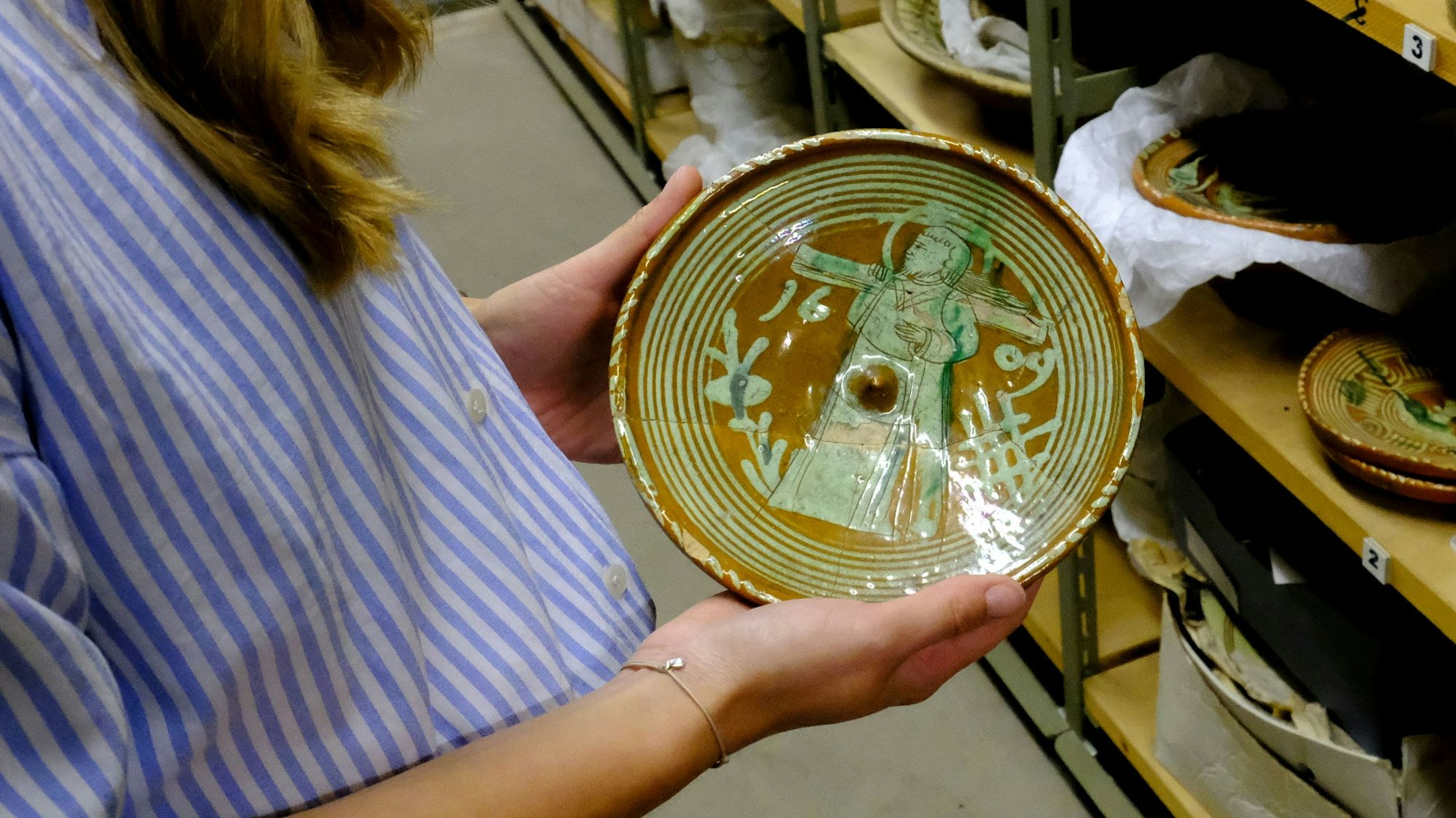 Michelle Klaiber hält einen reich verzierten Teller aus dem 17. Jahrhundert in Händen.