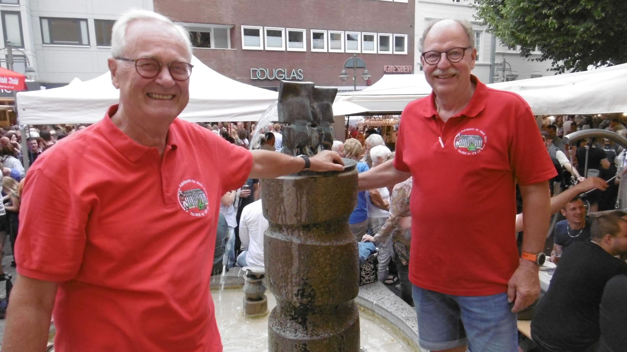 Zwei Männer in roten T-Shirts am Max-Ernst-Brunnen in Brühl.