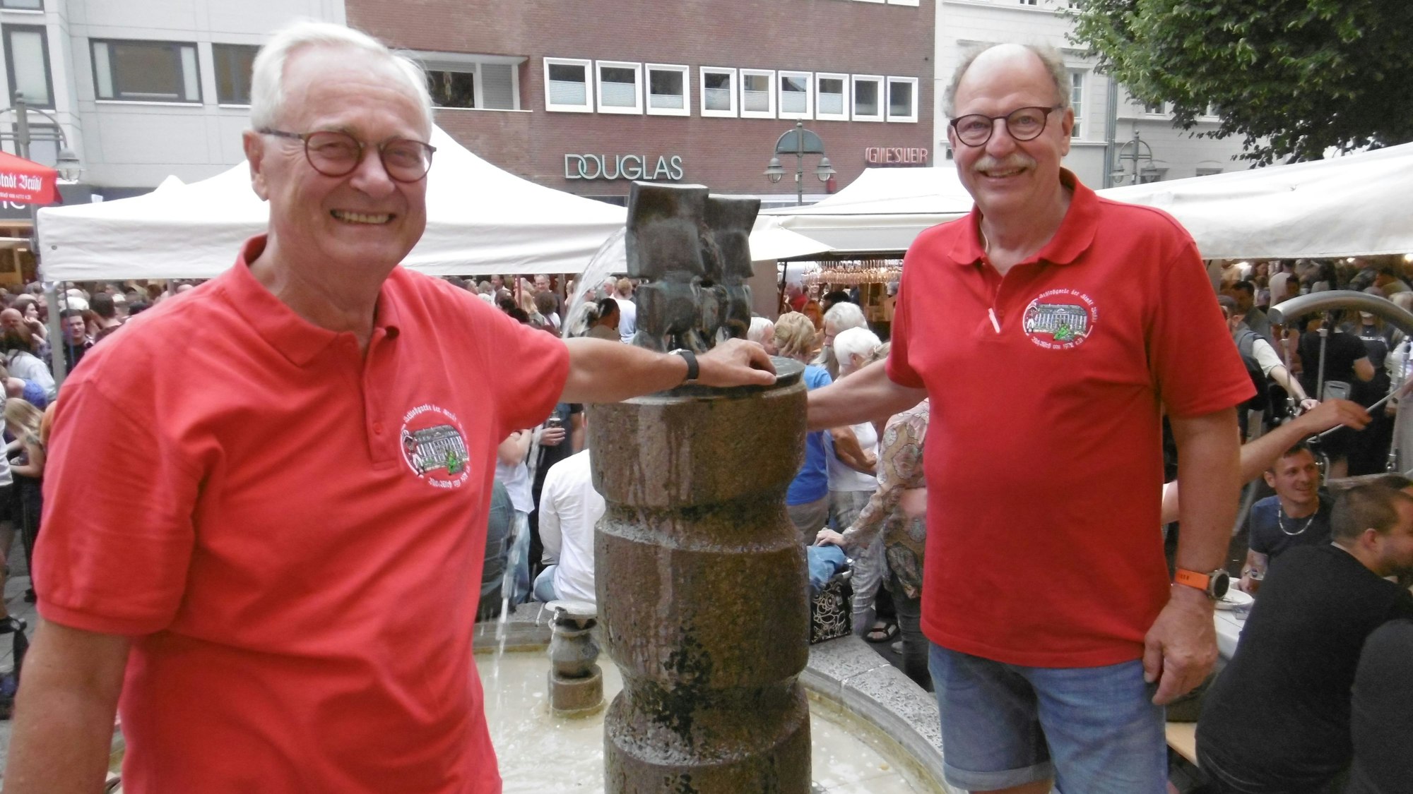 Zwei Männer in roten T-Shirts am Max-Ernst-Brunnen in Brühl.
