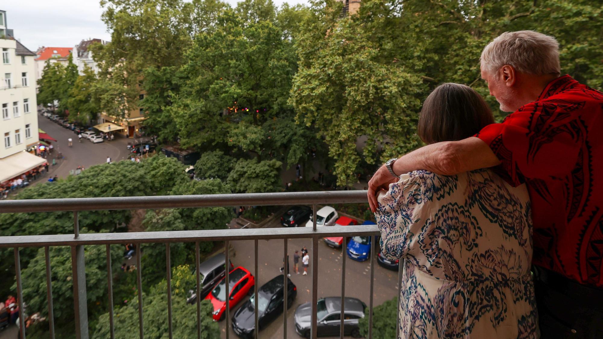 Ein Mann und eine Frau stehen in ihrer Wohnung und schauen auf den Brüsseler Platz.