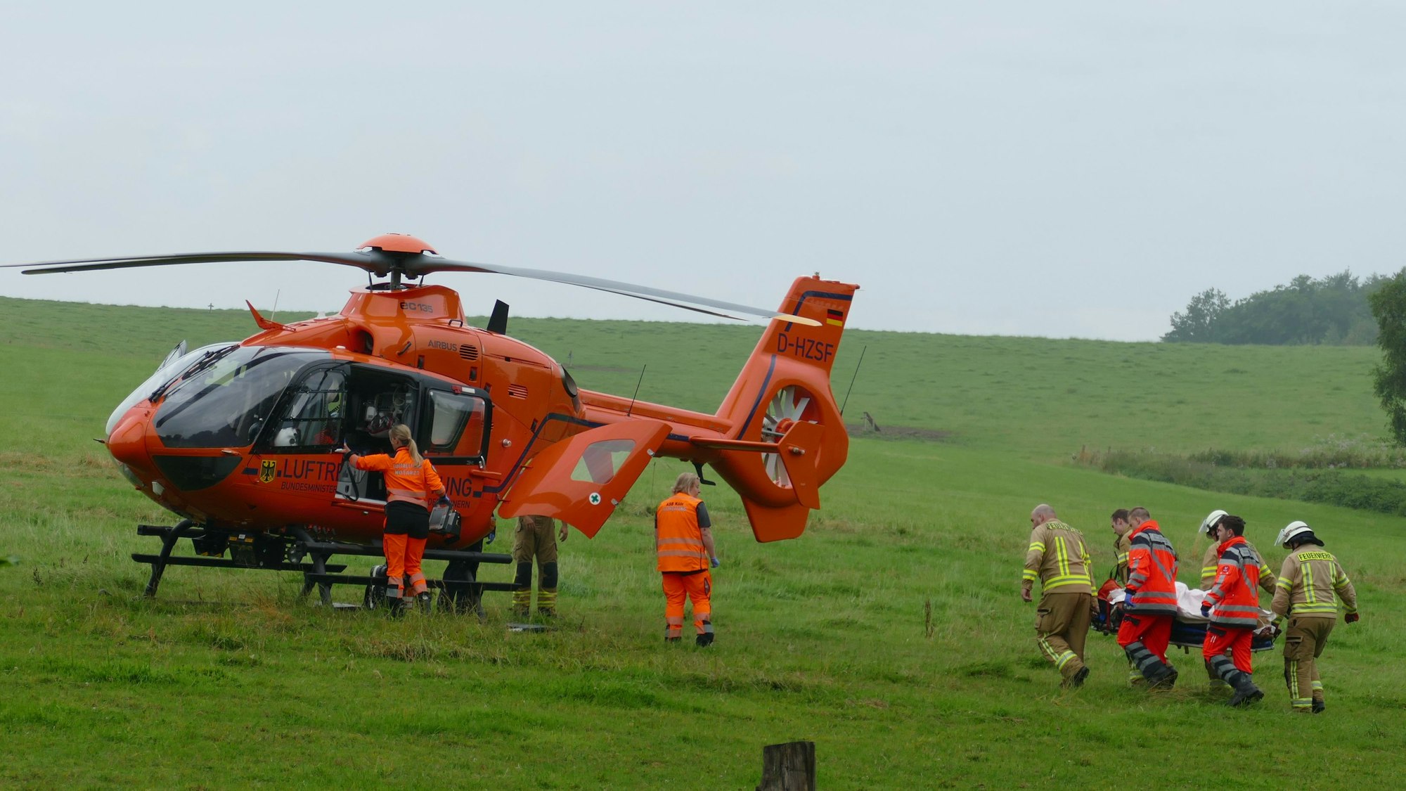 Feuerwehrleute tragen eine Patientin zu einem Rettungshubschrauber.