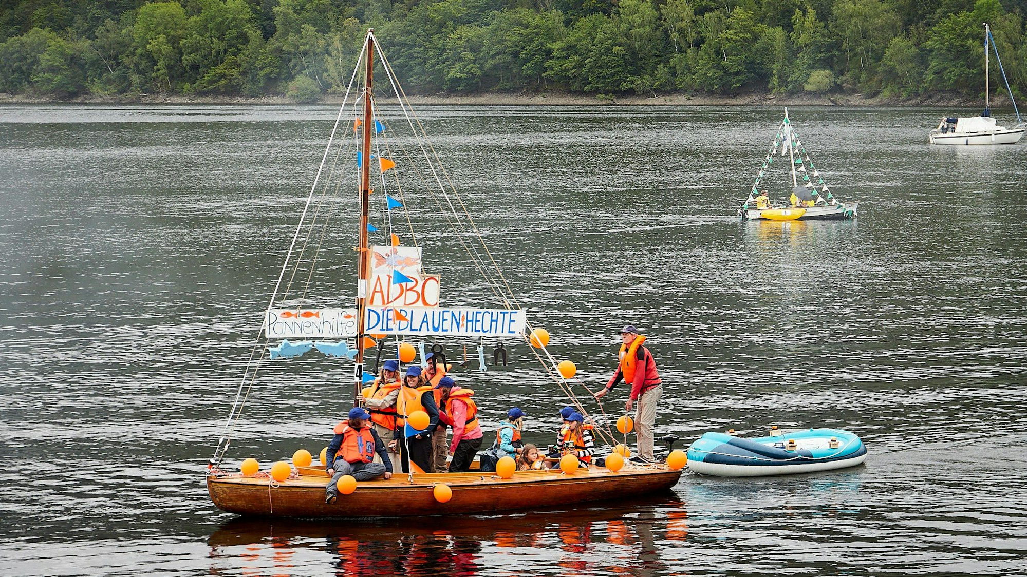 Bild von einem Segelboot, an dessen Mast „Pannenhilfe - Die Blauen Hechte“ zu lesen ist.