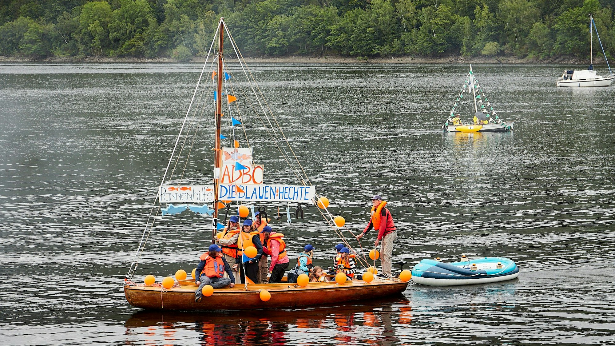 Bild von einem Segelboot, an dessen Mast „Pannenhilfe - Die Blauen Hechte“ zu lesen ist.