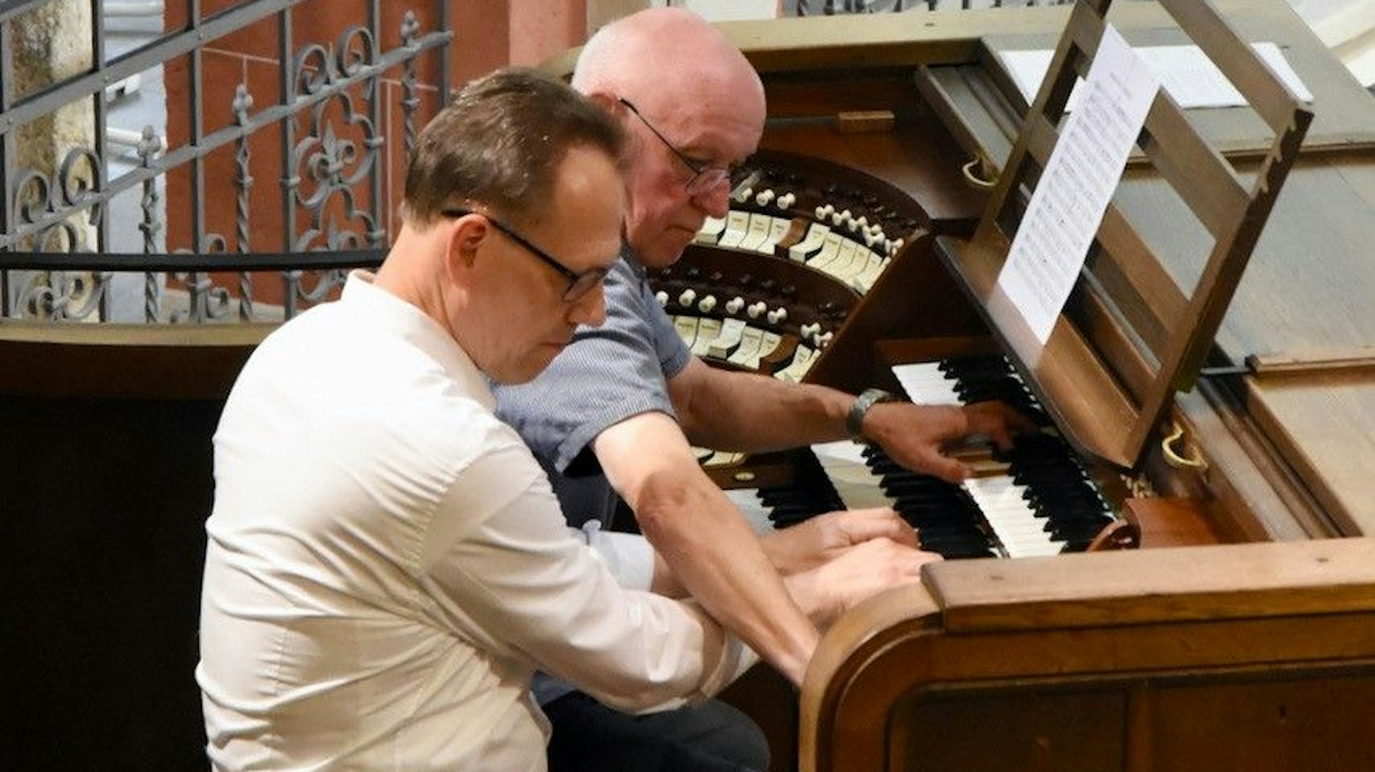Zwei Männer spielen gemeinsam an einer Orgel.