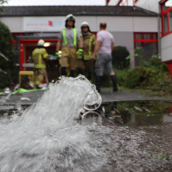 Zu sehen ist ein Wasserschlauch der Feuerwehr vor einem Gebäude. .