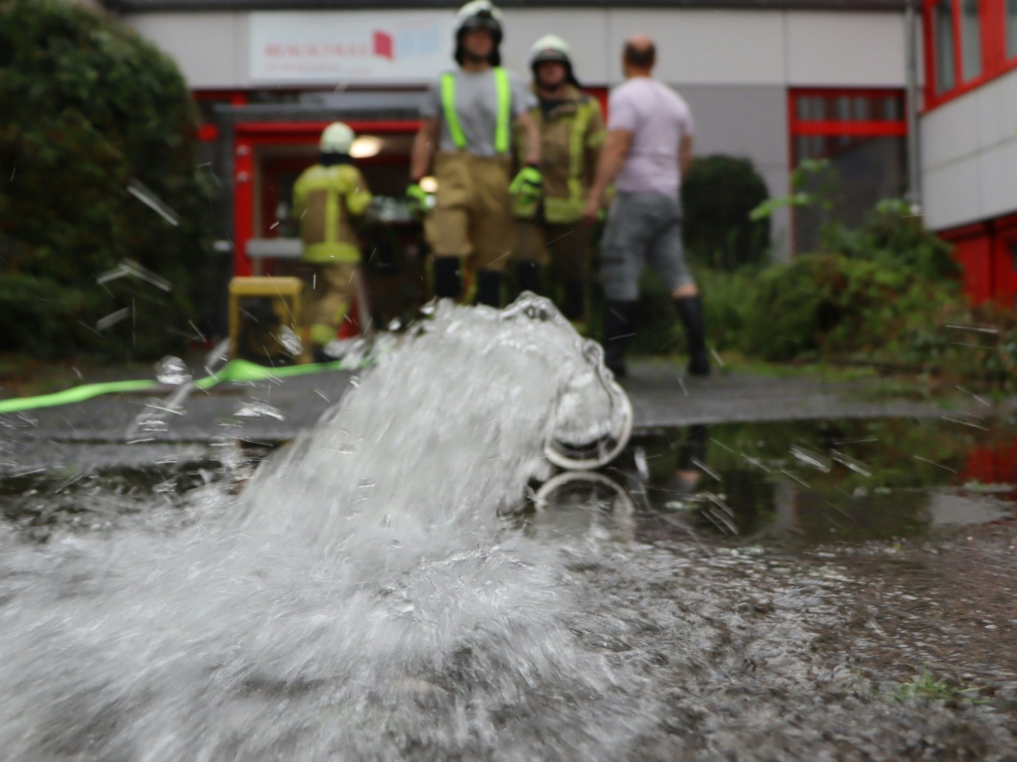 Das Bild zeigt Feuerwehrleute im Einsatz. Sie pumpen Wasser aus dem Gebäude der Realschule.