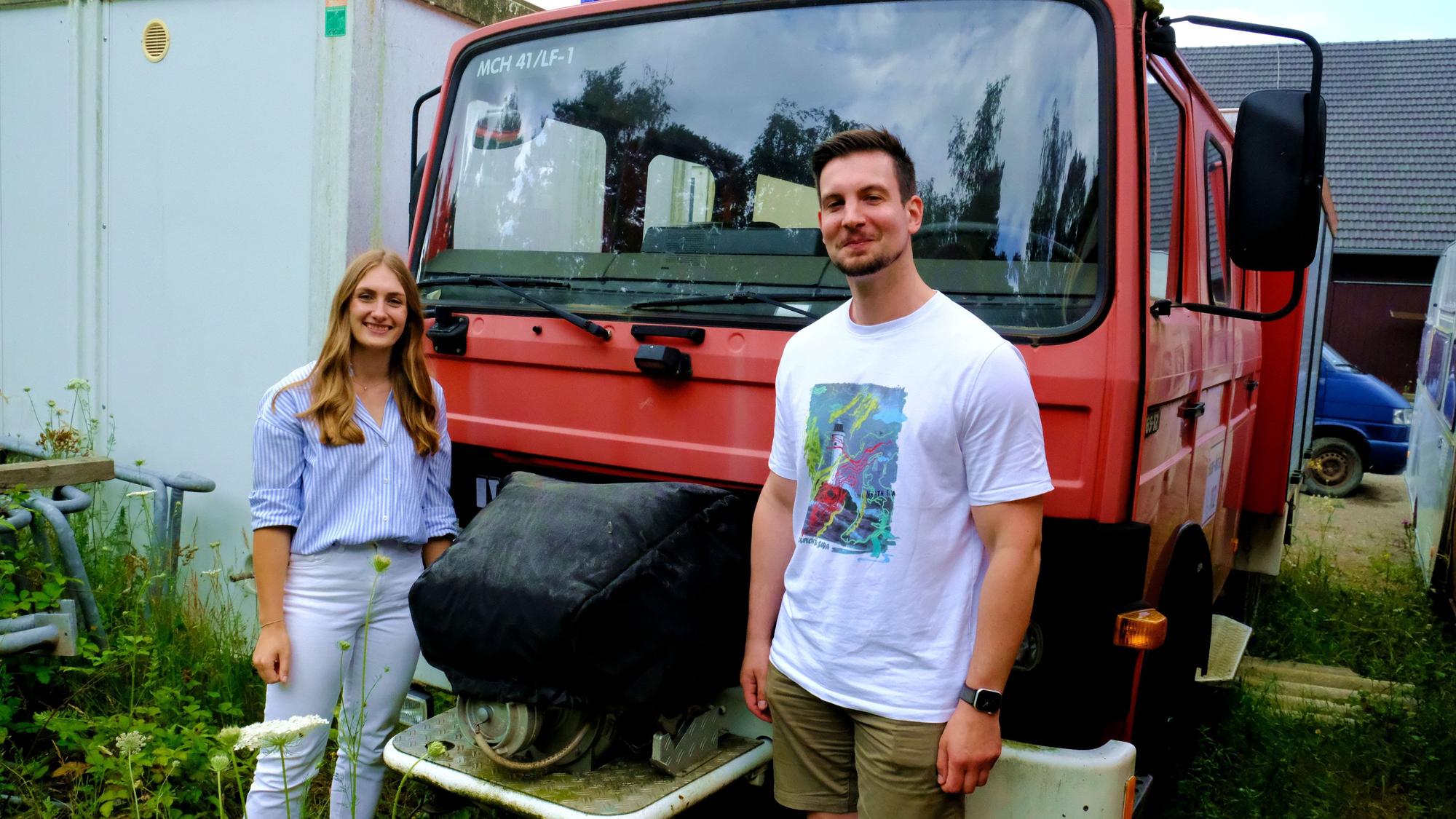 Michelle Klaiber und Jan Clevinghaus stehen vor einem ehemaligen Fahrzeug der Freiwilligen Feuerwehr Mechernich.