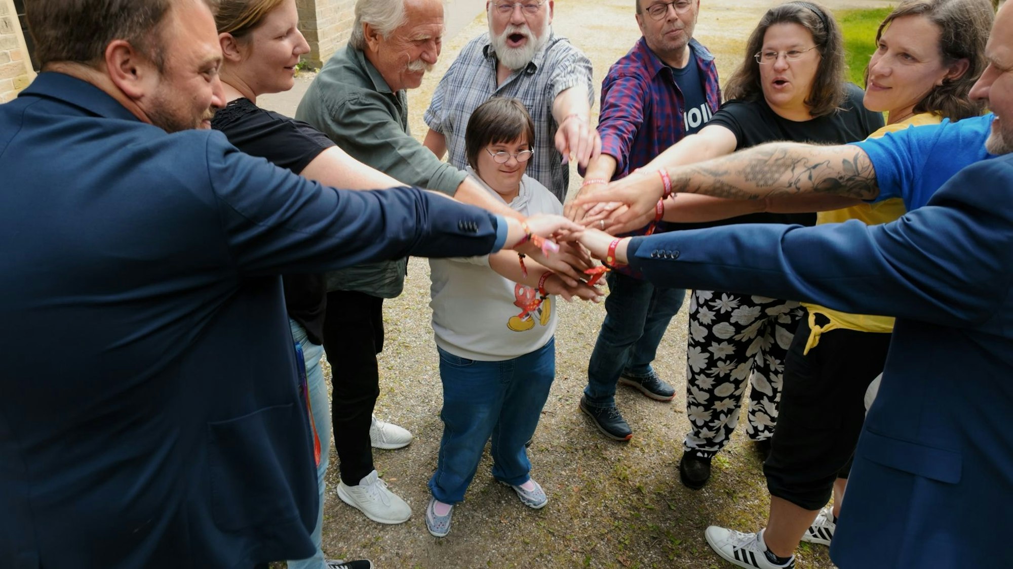 Männer und Frauen haben einen Kreis gebildet und berühren sich in der Mitte an den Händen.