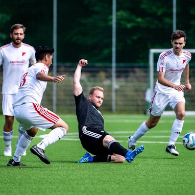 Das Bild zeigt Nierfedls Stürmer Sven Pohl, der den Ball vor drei Gegenspielern weggrätscht.